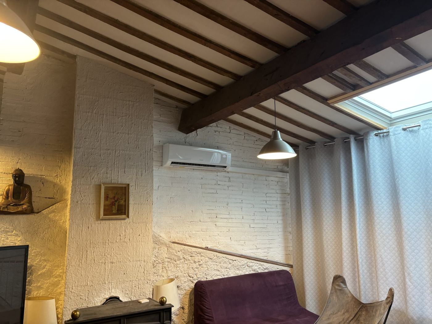 Climatisation murale installée dans une maison de village à poutres apparentes à Saint-Estève