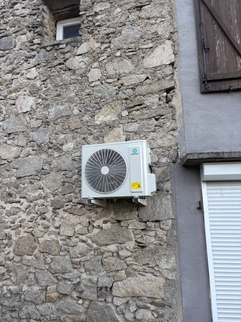 Groupe extérieur de climatisation fixé sur un mur en pierre