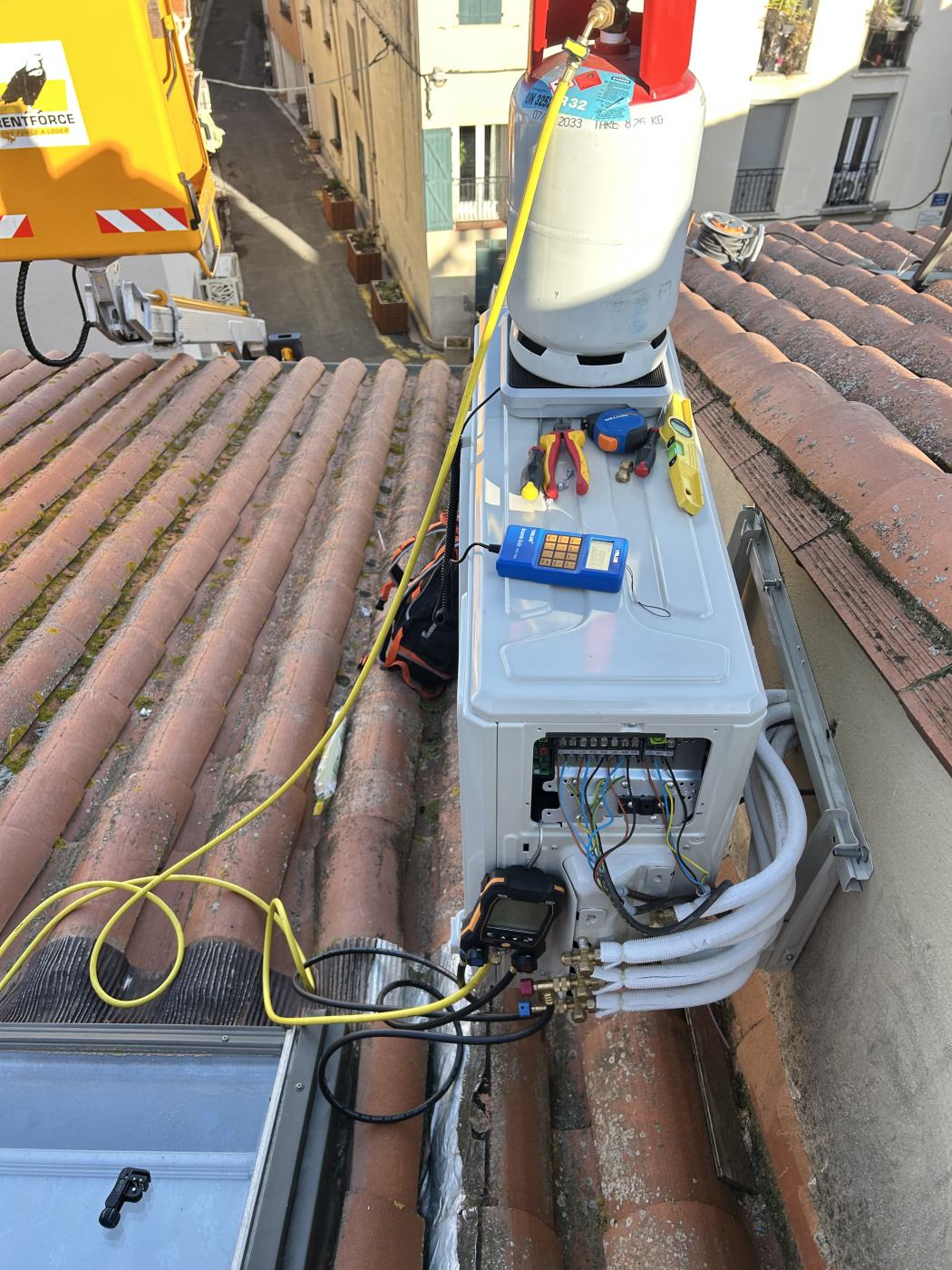 Dépannage d'une climatisation sur un toit à Elne : groupe extérieur ouvert, manomètres raccordés et bouteille de fluide R32