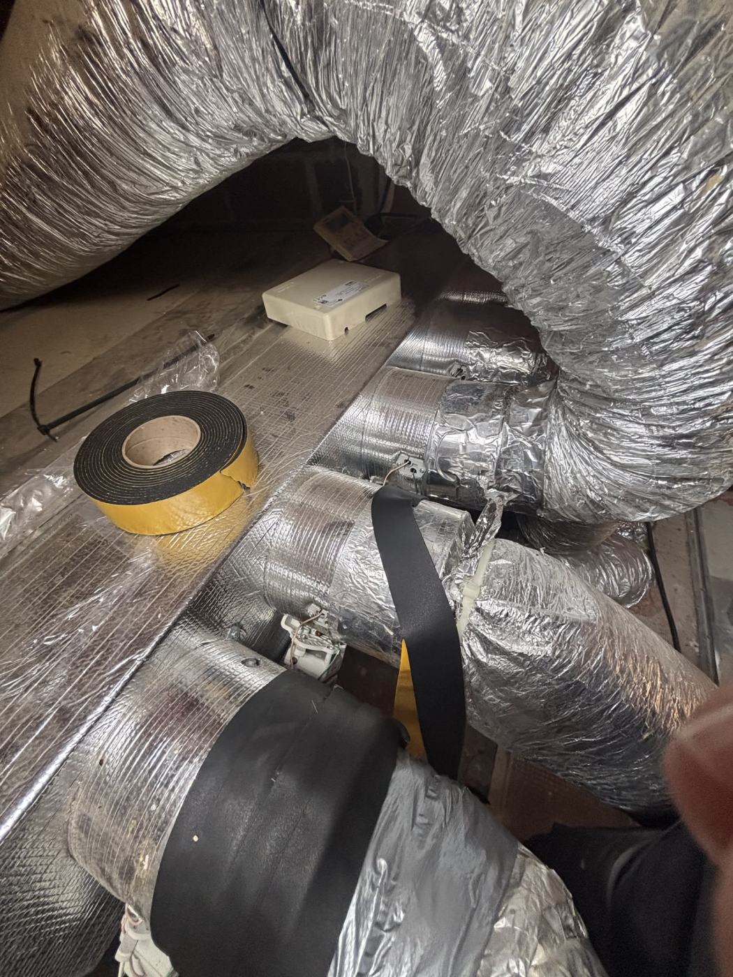 Gaines isolées raccordées au plénum d'une climatisation gainable, joints couverts d'adhésif isolant